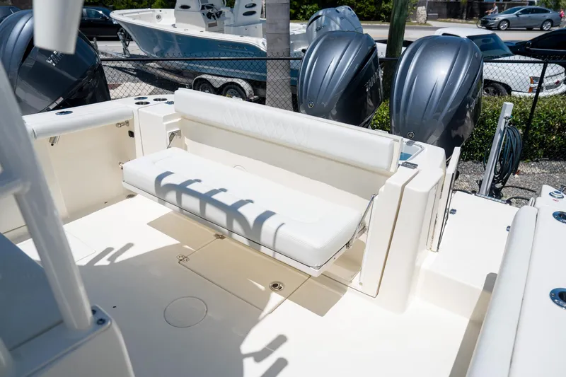Slide: The Image of 2024 Cobia 320 CC boat with white seating and dual outboard motors. - 26