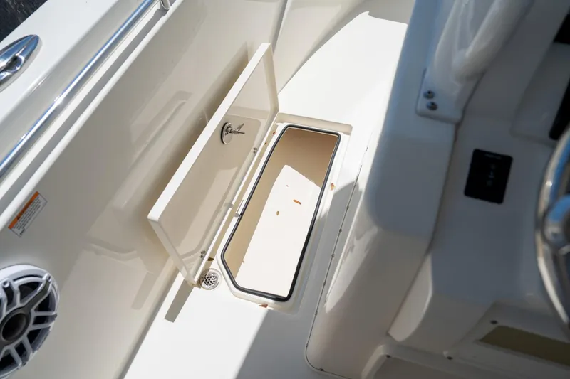 Slide: The Image of 2024 Cobia 320 CC boat storage compartment with open hatch and speaker. - 35