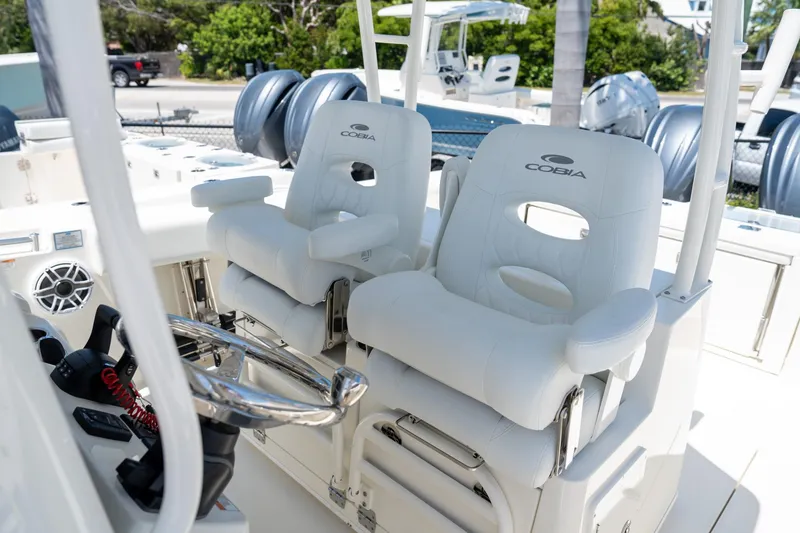 Slide: The Image of 2024 Cobia 320 CC boat interior with white cushioned seats and steering wheel. - 13