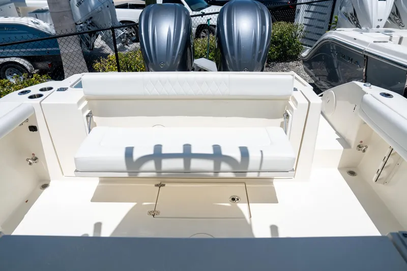 Slide: The Image of 2024 Cobia 320 CC boat interior with white seating and dual outboard motors. - 25
