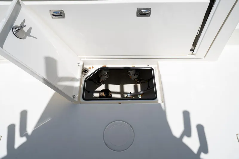 Slide: The Image of Open hatch on 2024 Cobia 320 CC boat deck, revealing storage compartment. - 32