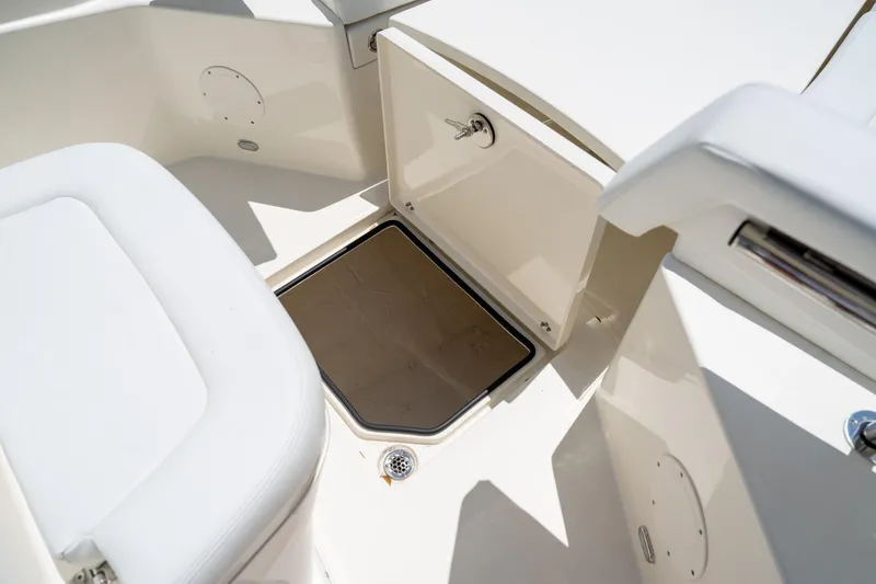 Slide: The Image of 2024 Cobia 320 CC boat interior storage compartment, open hatch, and seating area. - 44