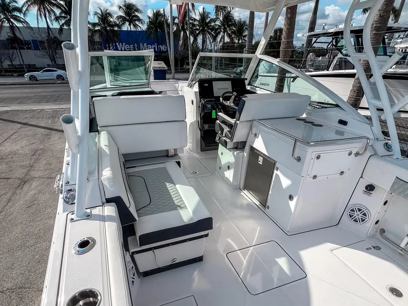 Slide: The Image of 2024 Blackfin 272DC boat interior with seating, helm, and storage, docked near palm trees. - 5