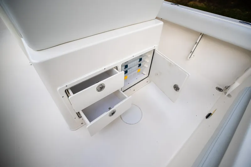Slide: The Image of 2024 Cobia 220 CC boat storage compartments with open drawers and cabinet. - 11