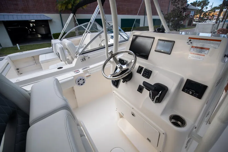 Slide: The Image of 2024 Cobia 220 CC boat cockpit with steering wheel and control panel. - 14