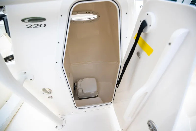Slide: The Image of 2024 Cobia 220 CC boat interior with compact marine toilet. - 28