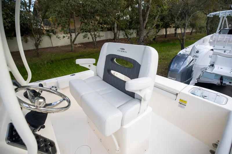 Slide: The Image of 2024 Cobia 220 CC boat interior with steering wheel and cushioned seating. - 13