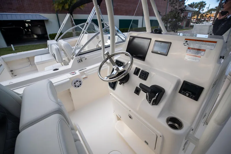 Slide: The Image of 2024 Cobia 220 CC boat cockpit with steering wheel and control panel. - 15