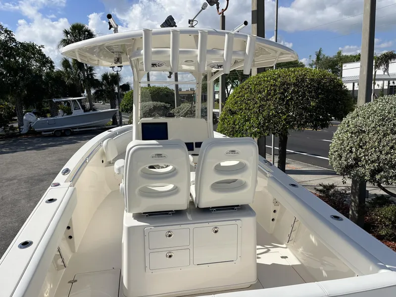 Slide: The Image of 2024 Cobia 262 CC boat interior with dual seats and console, parked outdoors. - 10
