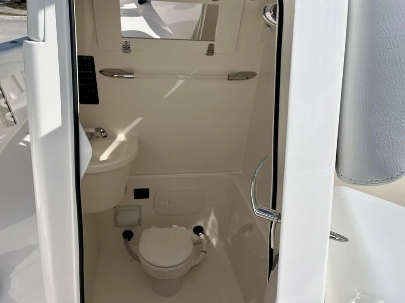 Slide: The Image of 2024 Cobia 262 CC boat interior with compact marine toilet and sink. - 18