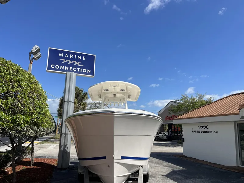 Slide: The Image of 2024 Cobia 262 CC boat at Marine Connection dealership under clear blue sky. - 3
