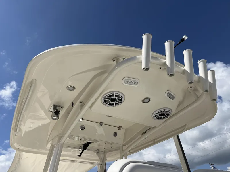 Slide: The Image of 2024 Cobia 262 CC boat top with rod holders and speakers against blue sky. - 33