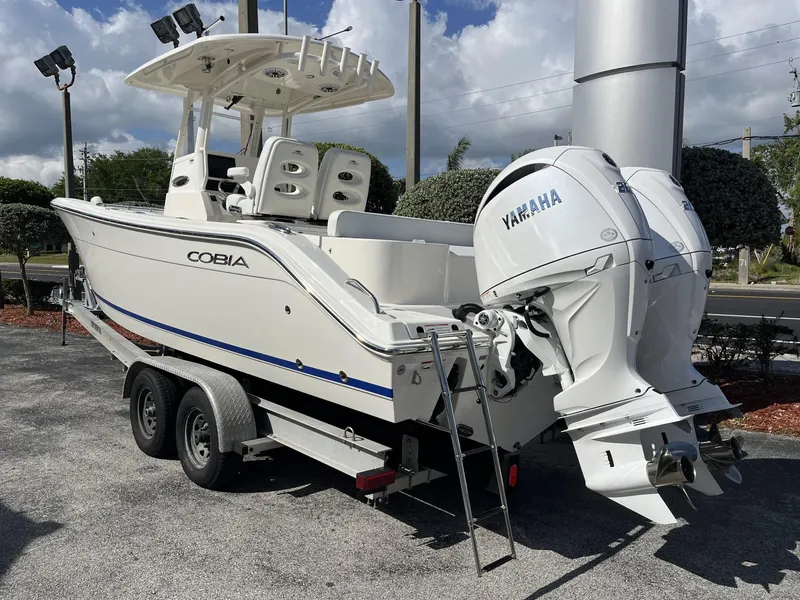 Slide: The Image of 2024 Cobia 262 CC boat on trailer with Yamaha engines, parked outdoors. - 4