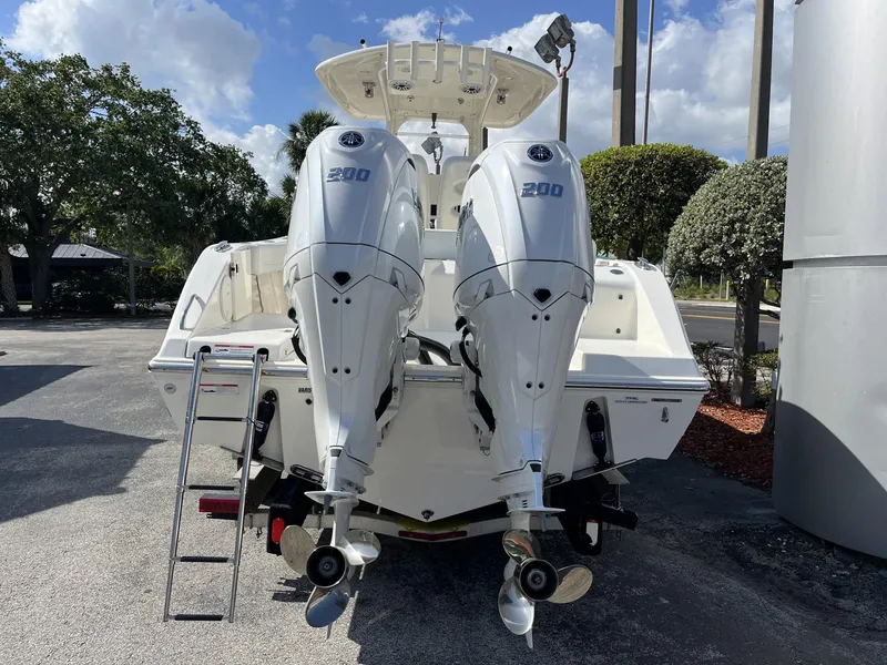 Slide: The Image of 2024 Cobia 262 CC boat with dual 200 horsepower engines, parked outdoors. - 5