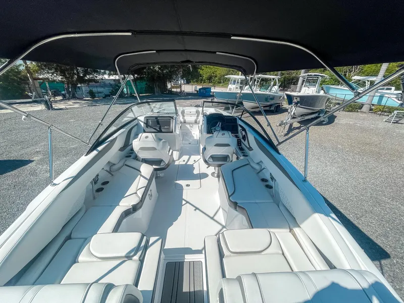 Slide: The Image of 2024 Hurricane SunDeck 2600 OB boat interior with seating and canopy, parked outdoors. - 10
