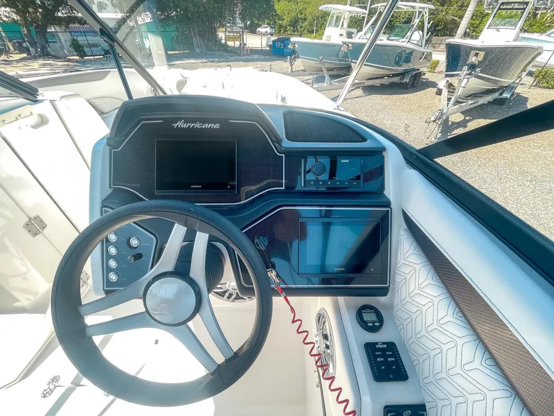Slide: The Image of 2024 Hurricane SunDeck 2600 OB boat dashboard with steering wheel and navigation controls. - 11