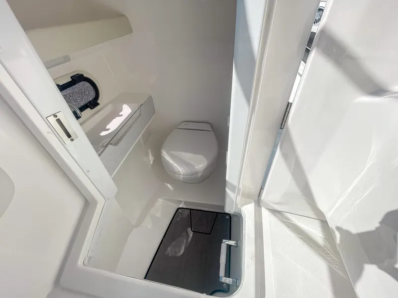 Slide: The Image of 2024 Hurricane SunDeck 2600 OB boat interior bathroom with toilet and storage. - 14