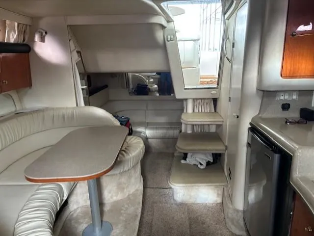 Slide: The Image of 2000 Sea Ray 340 Sundancer interior with seating, table, and compact kitchen area. - 18