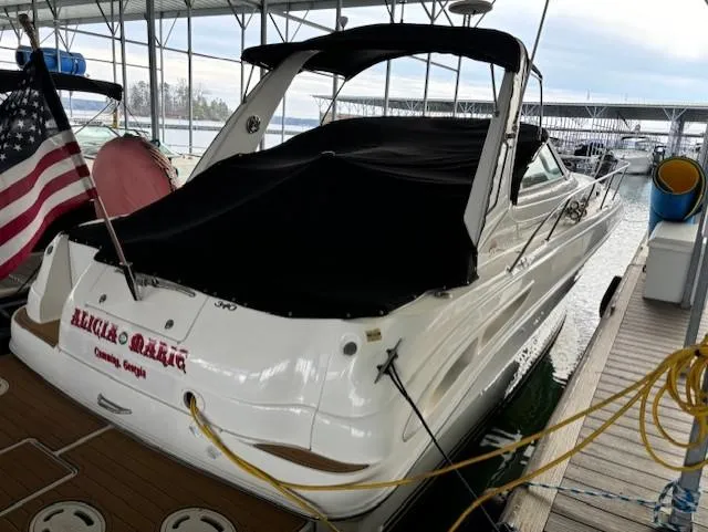 Slide: The Image of 2000 Sea Ray 340 Sundancer docked, covered, with American flag, in marina setting. - 2