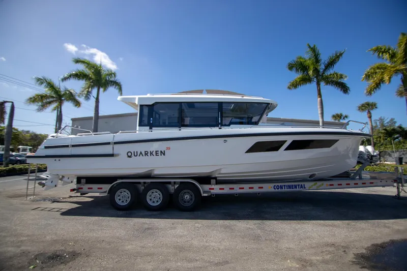 Slide: The Image of 2024 Quarken 35 Cabin boat on trailer, parked with palm trees in background. - 9