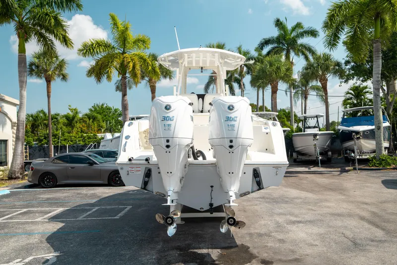Slide: The Image of 2024 Cobia 301 CC boat with dual engines, parked outdoors under palm trees. - 3