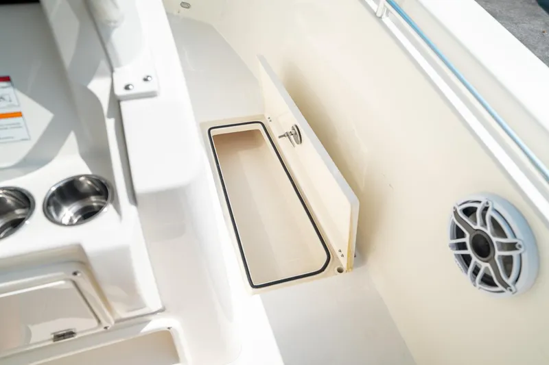 Slide: The Image of 2024 Cobia 301 CC boat interior with storage compartment and speaker. - 37