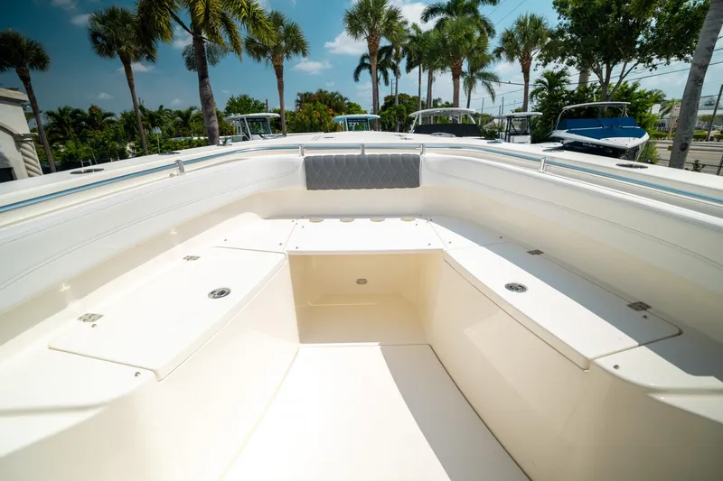 Slide: The Image of 2024 Cobia 301 CC boat interior with seating and storage, surrounded by palm trees. - 41