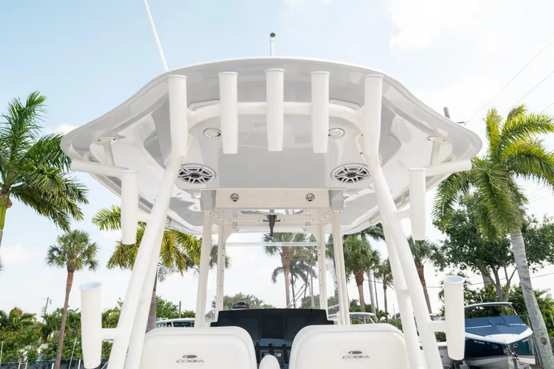 Slide: The Image of 2024 Cobia 301 CC boat with T-top and rod holders, surrounded by palm trees. - 13