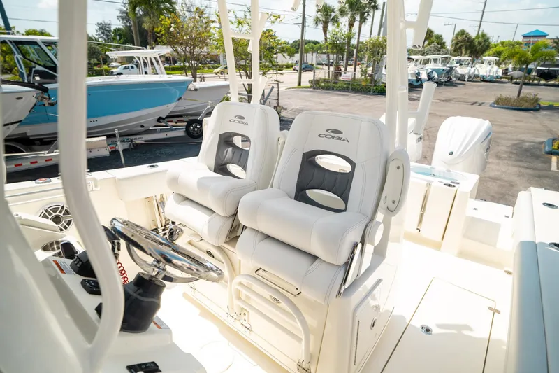 Slide: The Image of 2024 Cobia 301 CC boat interior with dual captain's chairs and steering wheel. - 19