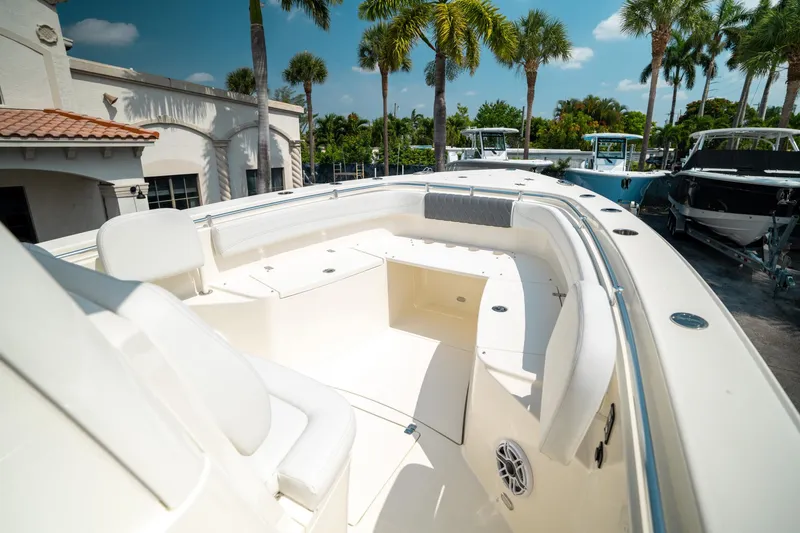 Slide: The Image of 2024 Cobia 301 CC boat interior with seating, docked under palm trees. - 40