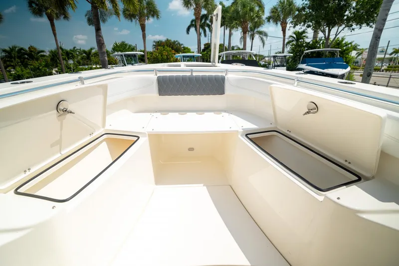 Slide: The Image of 2024 Cobia 301 CC boat interior with open storage compartments, surrounded by palm trees. - 43