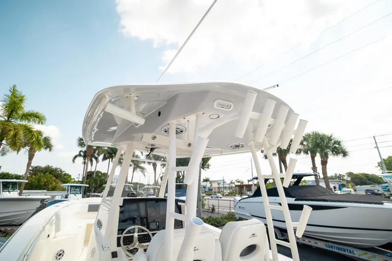 Slide: The Image of 2024 Cobia 301 CC boat with T-top and rod holders, docked under a sunny sky. - 15
