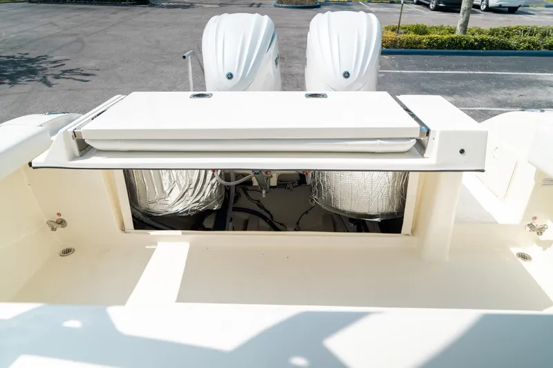 Slide: The Image of 2024 Cobia 301 CC boat with open storage compartment and dual engines. - 27