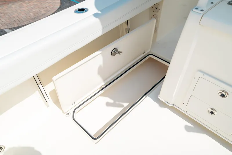 Slide: The Image of 2024 Cobia 301 CC boat storage compartment with open hatch and secure lock. - 33