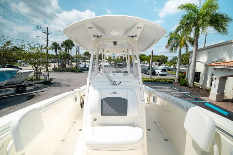 Slide: The Image of 2024 Cobia 301 CC boat with T-top, parked in a sunny marina setting. - 49