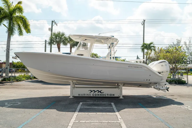 Slide: The Image of 2024 Cobia 301 CC boat displayed outdoors at Marine Connection dealership. - 5