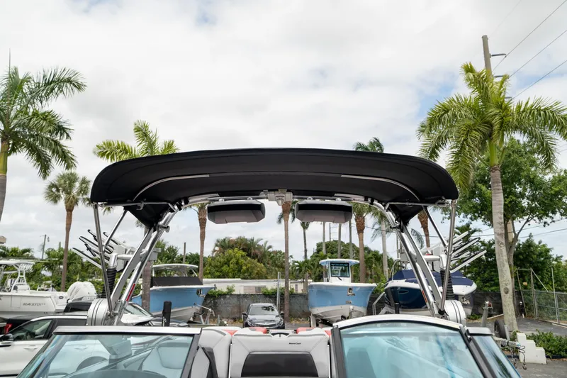 Slide: The Image of 2019 MasterCraft X-Star boat with canopy, surrounded by palm trees and other boats. - 29