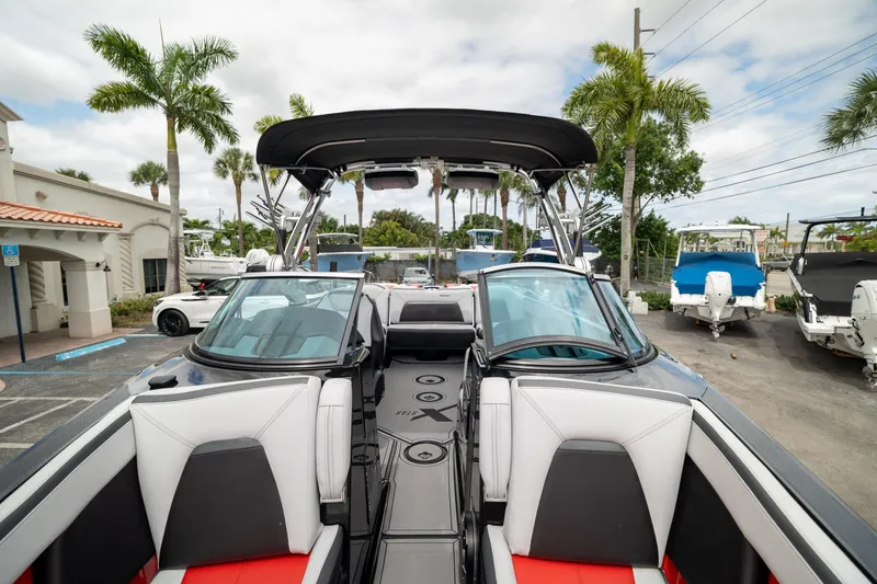 Slide: The Image of 2019 MasterCraft X-Star boat with sleek interior, parked outdoors under palm trees. - 30