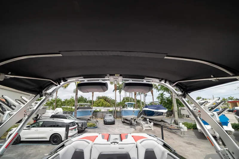 Slide: The Image of 2019 MasterCraft X-Star boat interior with canopy, parked near other boats and vehicles. - 35