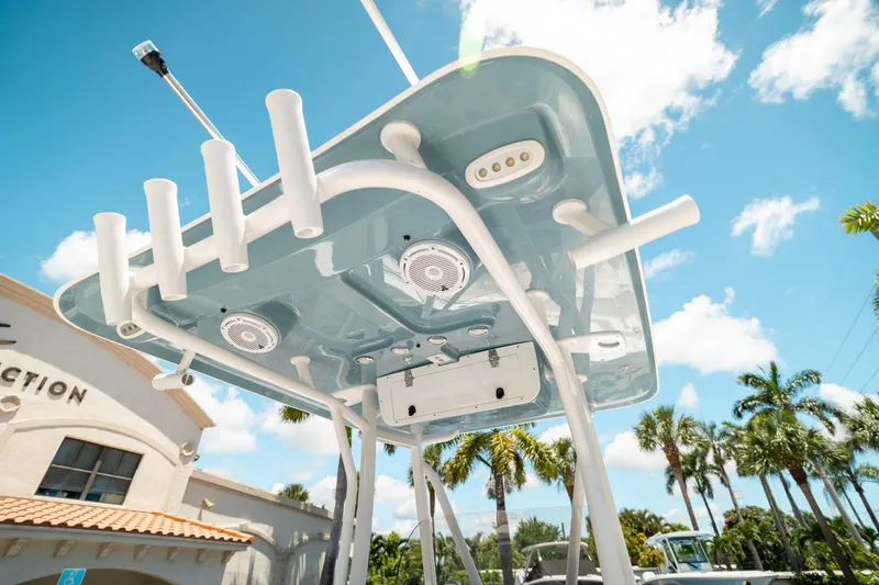 Slide: The Image of 2025 Sea Hunt Ultra 219 boat canopy with rod holders and speakers, under a clear blue sky. - 17