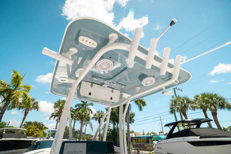 Slide: The Image of 2025 Sea Hunt Ultra 219 boat with T-top and rod holders under a clear blue sky. - 18