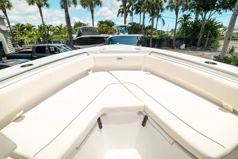 Slide: The Image of 2025 Sea Hunt Ultra 219 boat interior with cushioned seating, palm trees in background. - 32