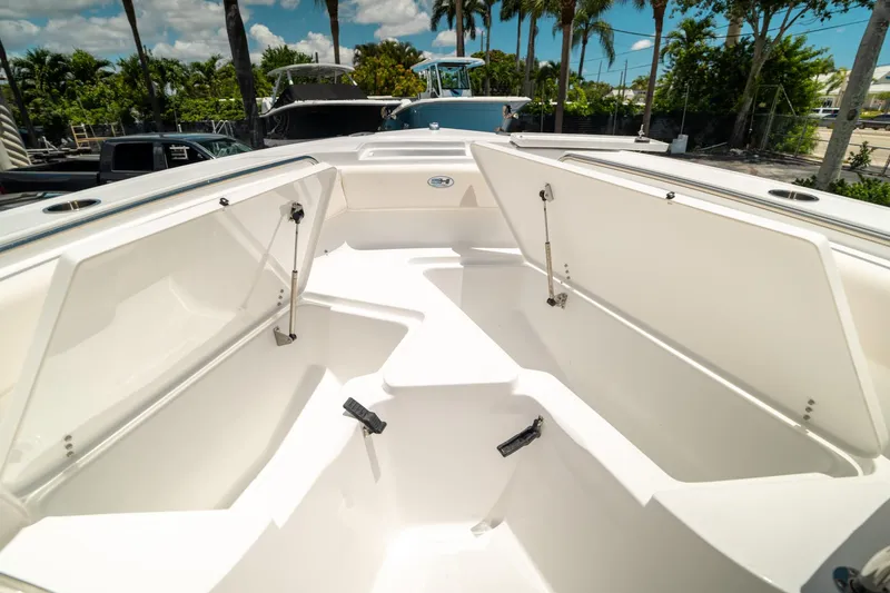Slide: The Image of 2025 Sea Hunt Ultra 219 boat interior with open storage compartments, surrounded by palm trees. - 35