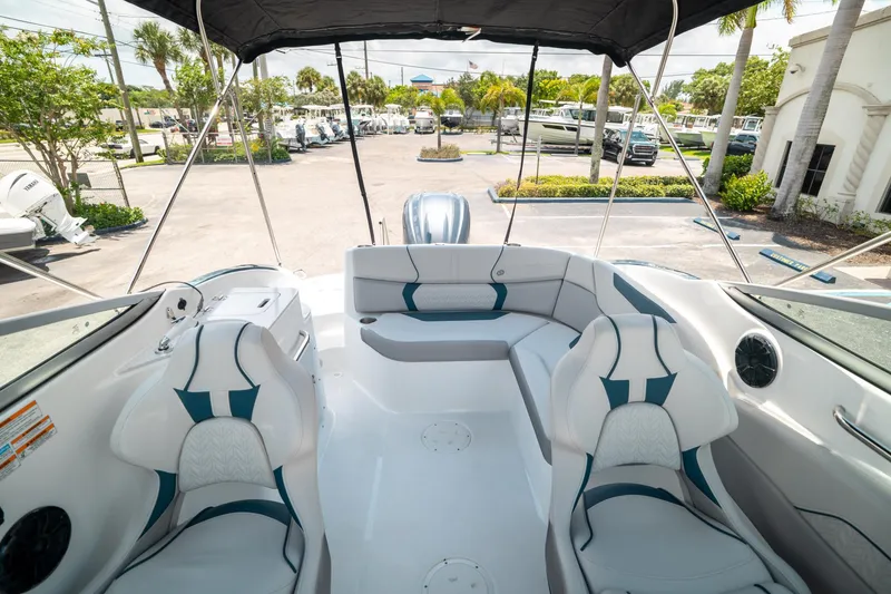 Slide: The Image of 2024 Hurricane SunDeck 2400 OB boat interior with seating and canopy in a sunny marina. - 10