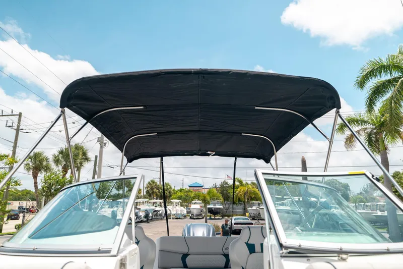 Slide: The Image of 2024 Hurricane SunDeck 2400 OB boat with canopy, parked outdoors under a clear sky. - 38