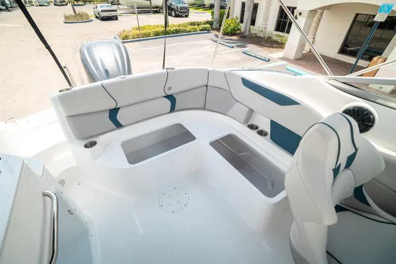 Slide: The Image of 2024 Hurricane SunDeck 2400 OB boat interior with white and blue seating, cup holders, and storage. - 12
