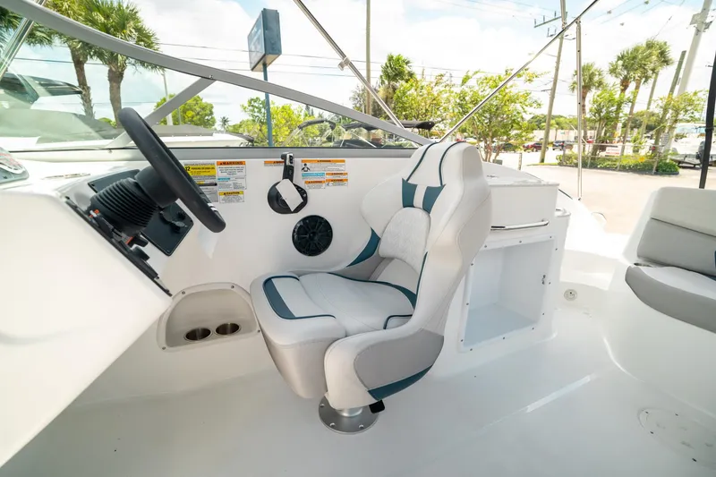 Slide: The Image of 2024 Hurricane SunDeck 2400 OB boat interior with captain's chair and steering wheel. - 22