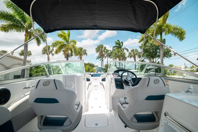 Slide: The Image of 2024 Hurricane SunDeck 2400 OB boat interior with steering wheel, seats, and palm trees in background. - 39