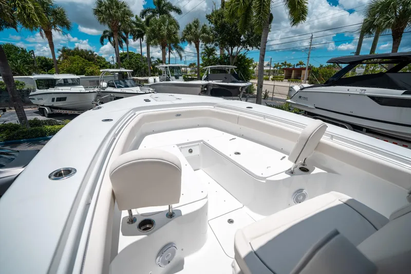 Slide: The Image of 2025 Sea Hunt Gamefish 28 FS boat interior with seating, surrounded by palm trees and other boats. - 41