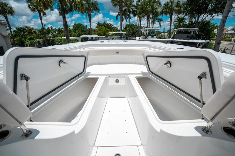 Slide: The Image of 2025 Sea Hunt Gamefish 28 FS boat with open storage compartments, surrounded by palm trees. - 44
